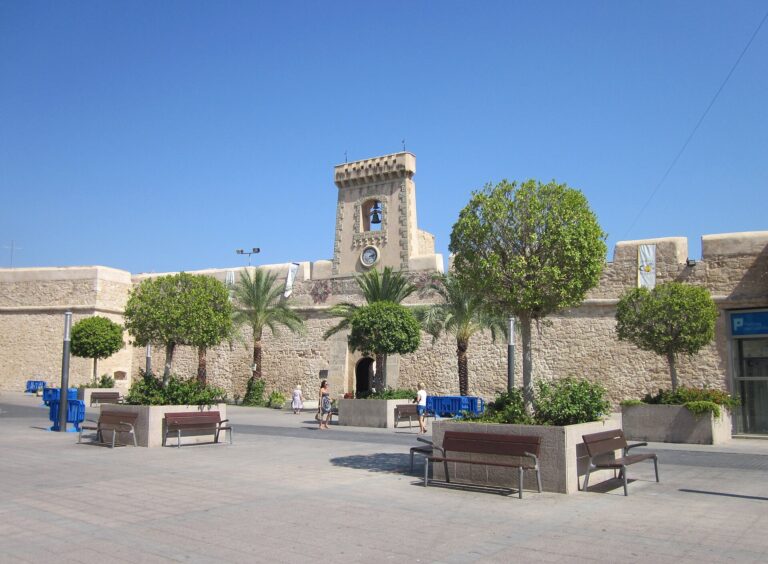 Castillo Fortaleza w Santa Pola z wieżą zegarową i palmami na placu, siedziba Museo del Mar