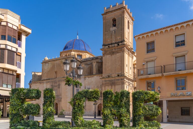 Bazylika Santa María w Elche z niebieską kopułą i zielonym napisem ELCHE na placu